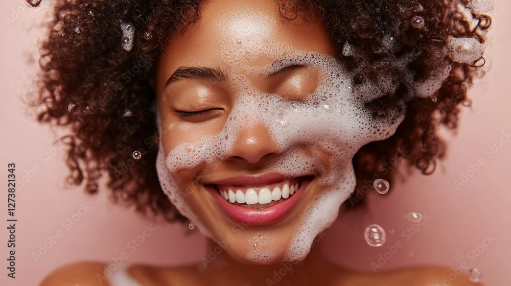 Fototapeta premium Close-up of a smiling woman with curly hair covered in soap bubbles, showcasing freshness and happiness, symbolizing skincare, beauty, and personal care in a joyful moment.
