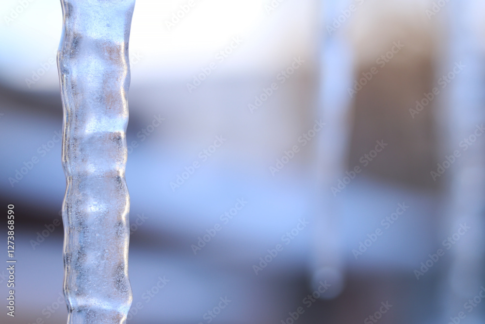 Icicles in the city close-up. Long icicle with selective focus. Winter. Frosty weather. Frozen water in winter, close-up. Icicles against the background of blurred buildings Icicles in the city close-up. Long icicle with selective focus. Winter. Frosty weather. Frozen water in winter, close-up. Icicles against the background of blurred buildings