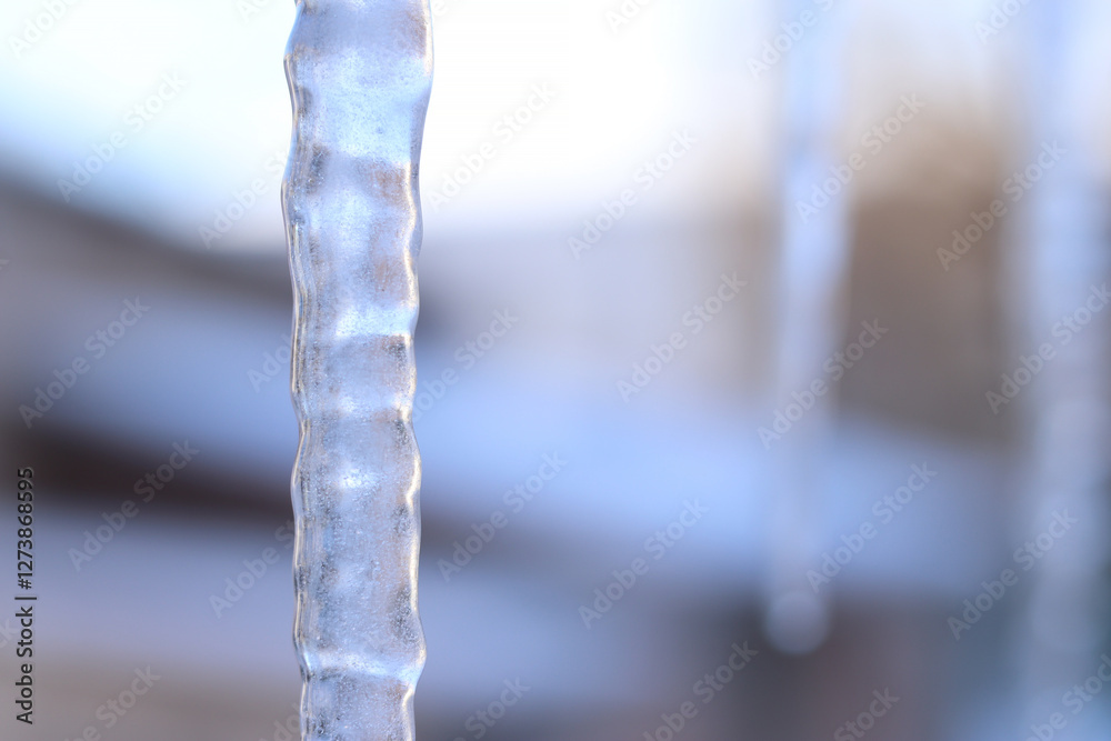 Icicles in the city close-up. Long icicle with selective focus. Winter. Frosty weather. Frozen water in winter, close-up. Icicles against the background of blurred buildings Icicles in the city close-up. Long icicle with selective focus. Winter. Frosty weather. Frozen water in winter, close-up. Icicles against the background of blurred buildings