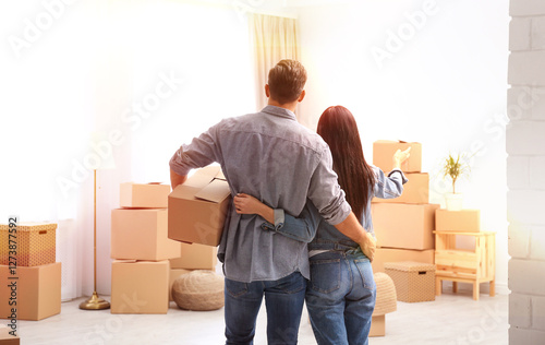 Canvas Print Happy couple in sunlit room with cardboard boxes on moving day