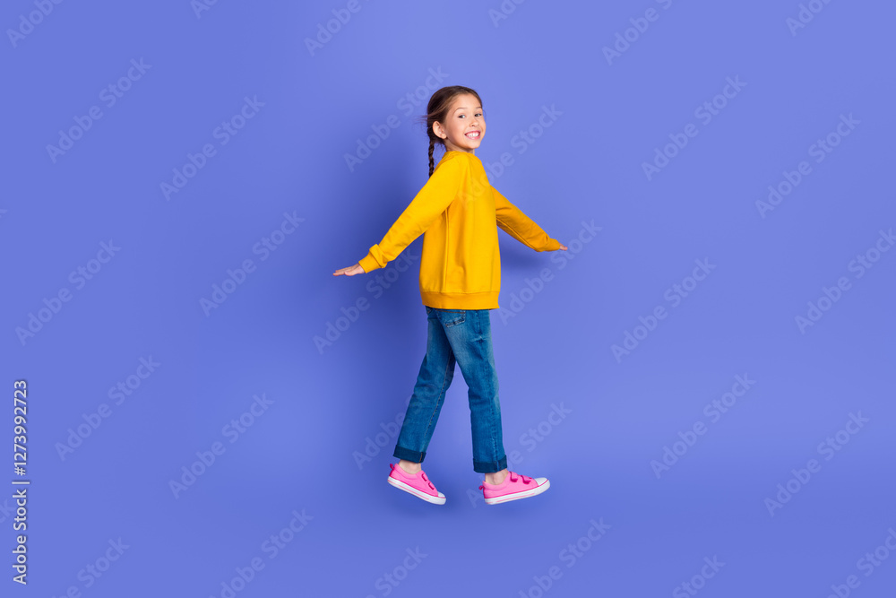 Portrait of a charming young girl in a bright yellow pullover against a vibrant purple backdrop, displaying happiness Portrait of a charming young girl in a bright yellow pullover against a vibrant purple backdrop, displaying happiness
