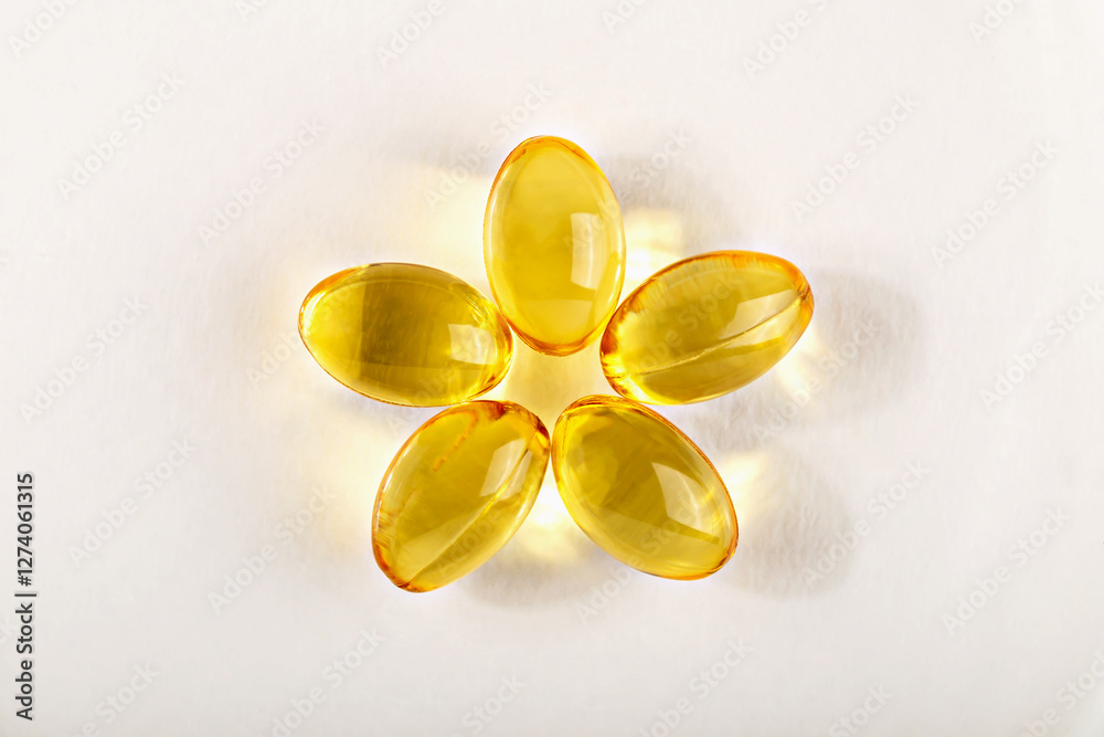Transparent yellow capsules forming flower like design on white surface, symbolizing health and wellness. Concept of natural supplements and nutritional balance. Healthcare or supplements Transparent yellow capsules forming flower like design on white surface, symbolizing health and wellness. Concept of natural supplements and nutritional balance. Healthcare or supplements