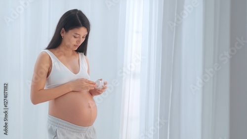 Young happy Asian pregnant woman posing in studio with white curtains in background Free Download Young happy Asian pregnant woman posing in studio with white curtains in background - GFXLoad