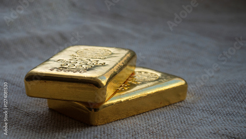 Cast gold bars on the background to the coarse texture of the textile. Selective focus.