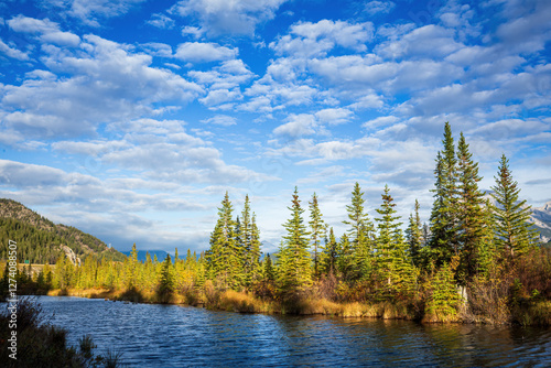 Vermilion Lake with stunning reflections of Mount Rundle, surrounded by evergreen trees and golden autumn hues. A breathtaking view of Banff National Park in the Canadian Rockies.