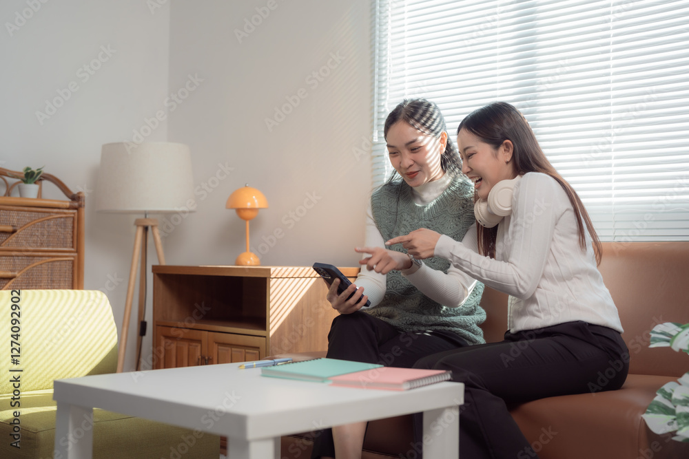 Two young women sitting on a couch, engaging with social media on a smartphone. They appear relaxed and happy, sharing content and ideas in a cozy living room setting Two young women sitting on a couch, engaging with social media on a smartphone. They appear relaxed and happy, sharing content and ideas in a cozy living room setting