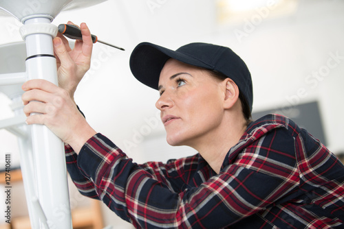 female driving a screw into chair