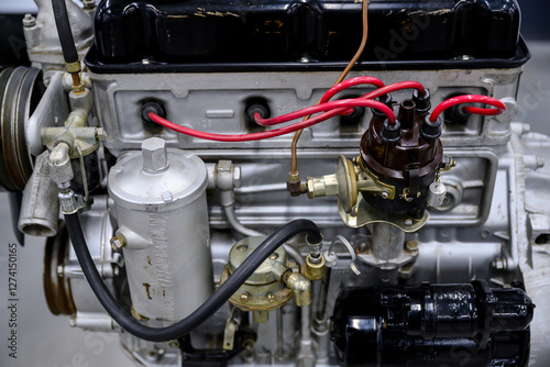The engine of a mid-20th century truck with a carburetor and candles