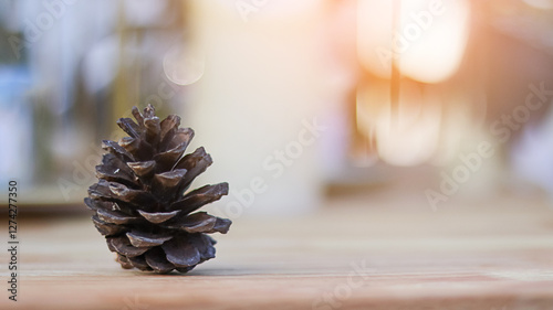 Blurred dried pine fruit on wooden table with blurred sun light in background