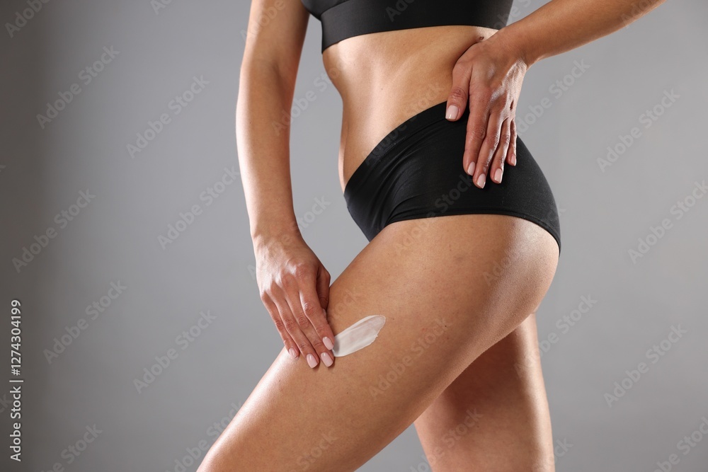 Fototapeta premium Woman applying anti cellulite cream on grey background, closeup