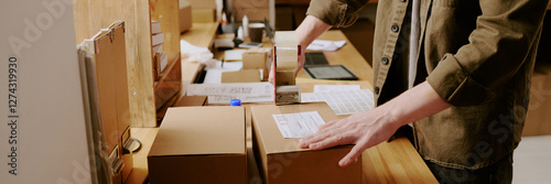 Cuadro en lienzo Worker sealing boxes with a packing tape machine in warehouse environment showin