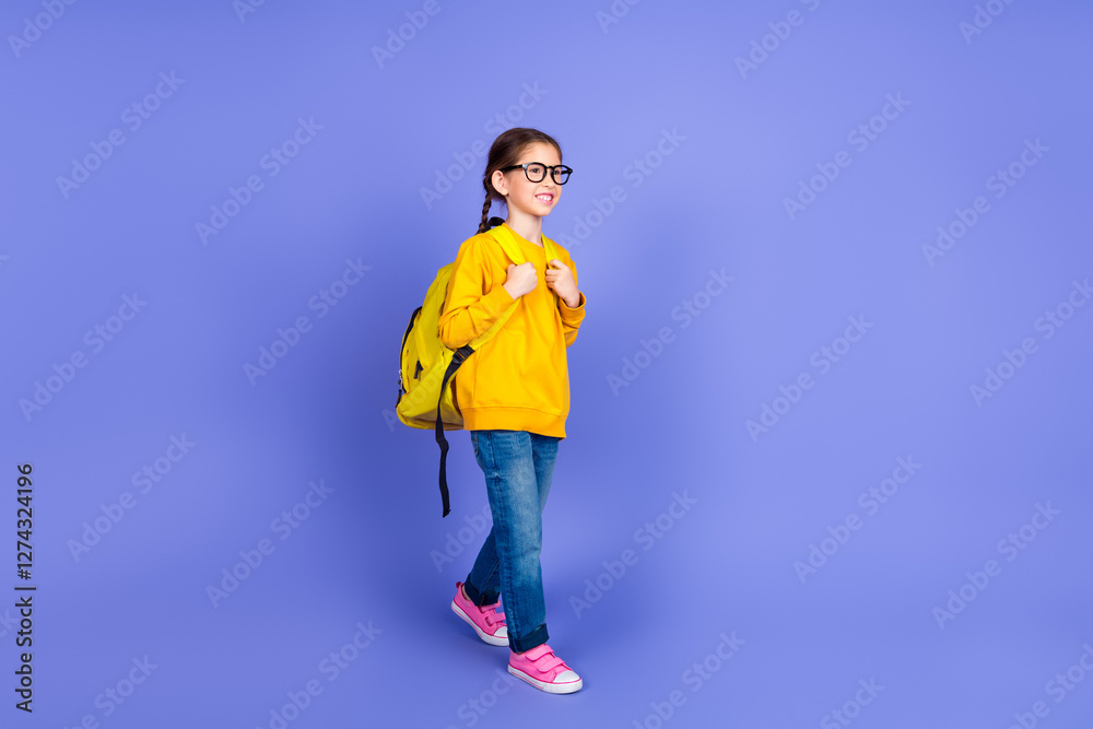 Young girl in casual attire with backpack walking confidently on violet background, showcasing trendy fashion and cheerful lifestyle. Young girl in casual attire with backpack walking confidently on violet background, showcasing trendy fashion and cheerful lifestyle.