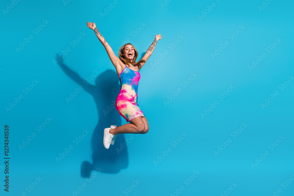 Happy young woman in colorful dress jumping with joy on a vibrant blue background showcasing enthusiasm and positive feelings Happy young woman in colorful dress jumping with joy on a vibrant blue background showcasing enthusiasm and positive feelings