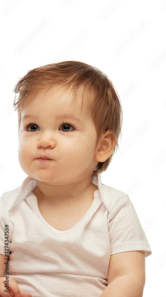 Close-up portrait of baby sitting with lips pursed and thoughtful expression while looking slightly sideways against white background. Concept of childhood, emotion, curiosity, early thoughts Close-up portrait of baby sitting with lips pursed and thoughtful expression while looking slightly sideways against white background. Concept of childhood, emotion, curiosity, early thoughts