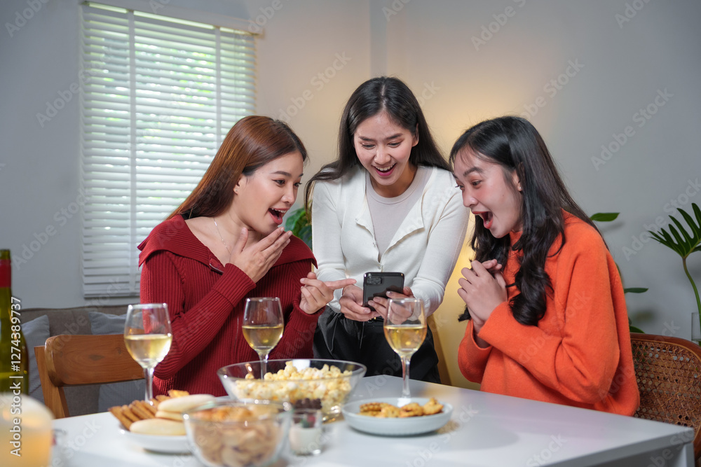 Surprised friends looking at smartphone enjoying home party with snacks and drinks Surprised friends looking at smartphone enjoying home party with snacks and drinks