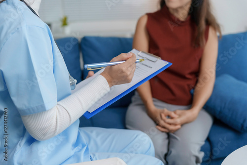 Female doctor taking notes while interviewing patient at home