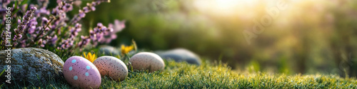 Polka-dotted Easter eggs on green grass and flowers in sunlight photo