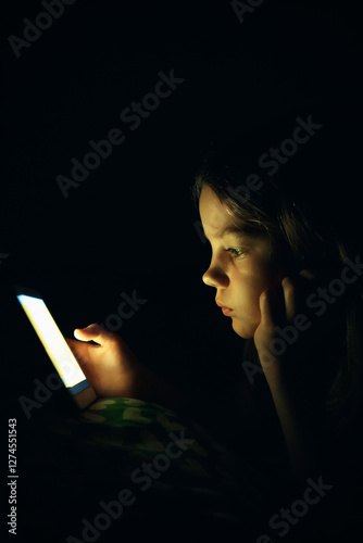 Girl with smartphone . Teenage girl is looking at the smartphone screen in the dark. Sad girl in the darkness reads on a smartphone news. Addiction to social networks concept