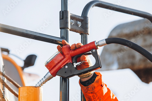 Canvas-taulu Worker fueling heavy machinery with a gas pump at a construction site during the