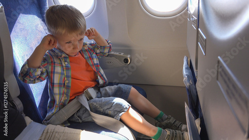 Tablou pe pânză Little child put hands on ears in the airplane, annoying loud sound and press
