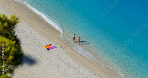 Top view of couple standing on beach with feet in the water waves