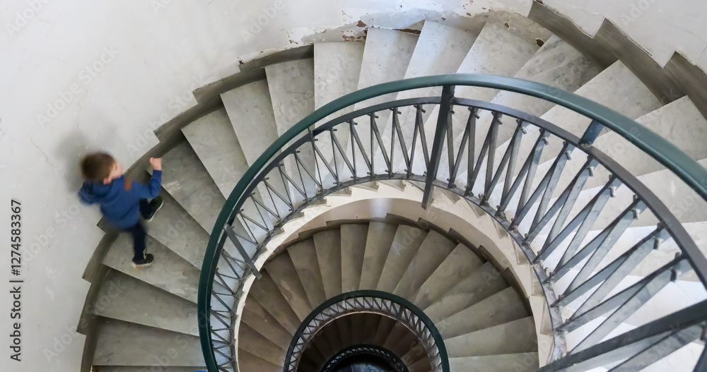 Fototapeta premium One small child going down the spiral stairs