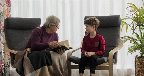 Pretty kid and his grandmother sharing thoughts after reading a book