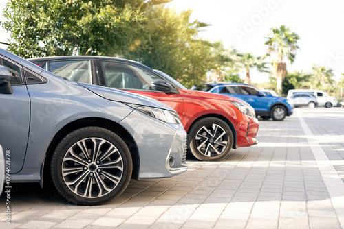 A row of new colorful vehicles on the parking. A line of used cars and trucks for sale.