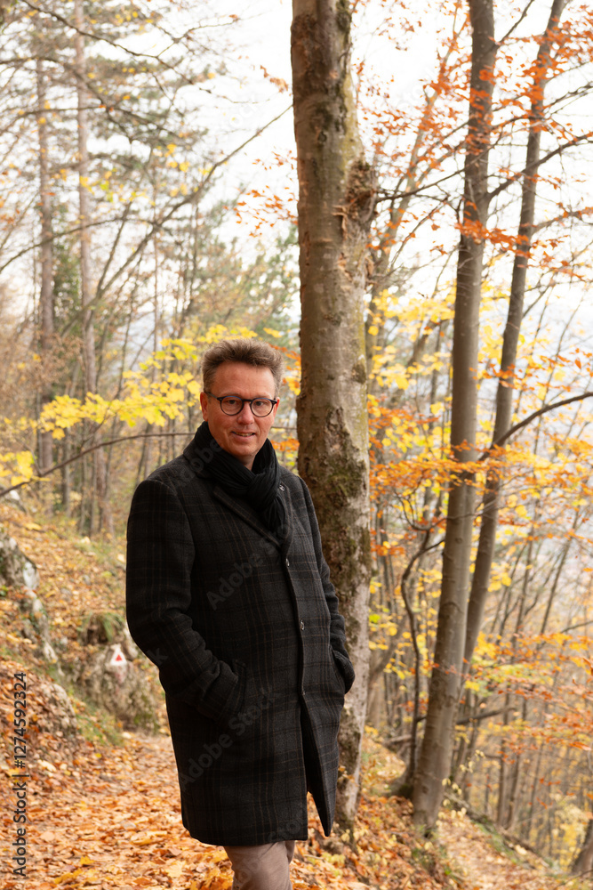 Caucasian man in autumn jacket and clothing posing on a forest trail, trees with autumn colors. The man is looking into the camera. Easy hiking trail in Brasov, Romania on Tampa mountain. Caucasian man in autumn jacket and clothing posing on a forest trail, trees with autumn colors. The man is looking into the camera. Easy hiking trail in Brasov, Romania on Tampa mountain.