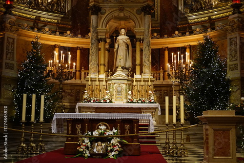 Close up of the ornate golden altar with Christmas decorations and a marble statue at St. Stephen's Basilica, Catholic church in Budapest, Hungary