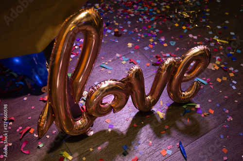 Metallic love balloon on vibrant confetti-covered floor