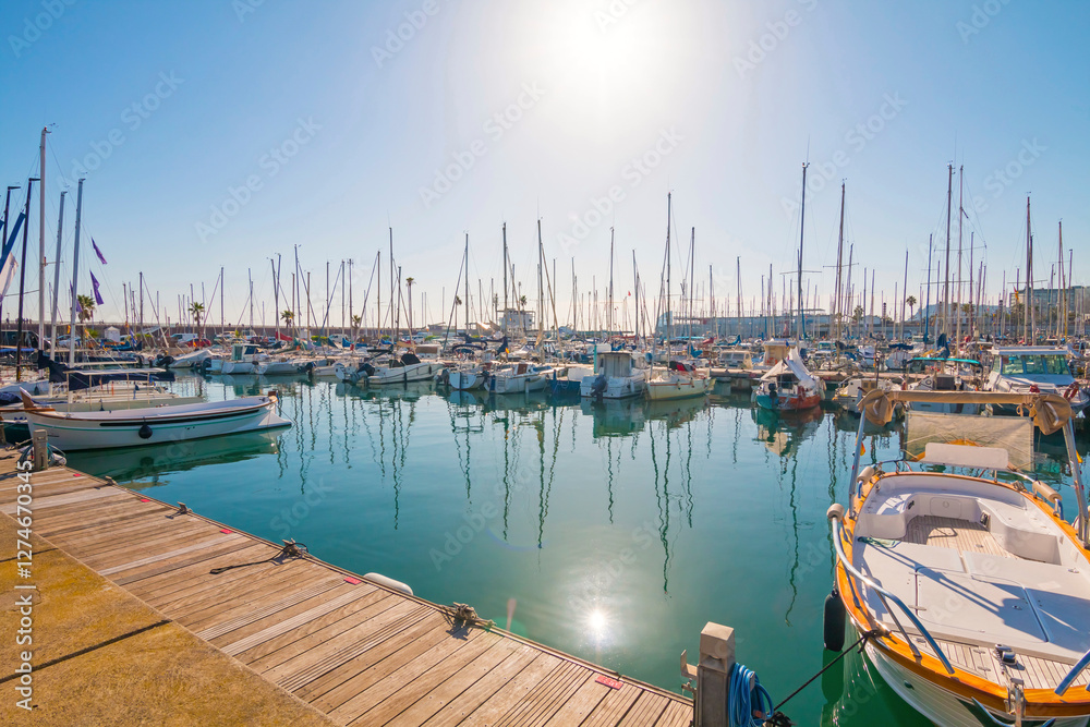 Port Olímpic Marina in Barcelona on a sunny day, featuring luxury yachts, clear blue skies, and a vibrant waterfront atmosphere along the Mediterranean coast.