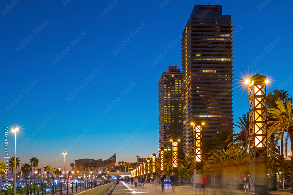 Barcelona Marina at night shines with city lights reflecting on the water, featuring elegant yachts, a vibrant atmosphere, and stunning views of the Mediterranean coast