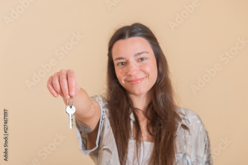 Young woman holding house keys in welcoming gesture at the moving photo