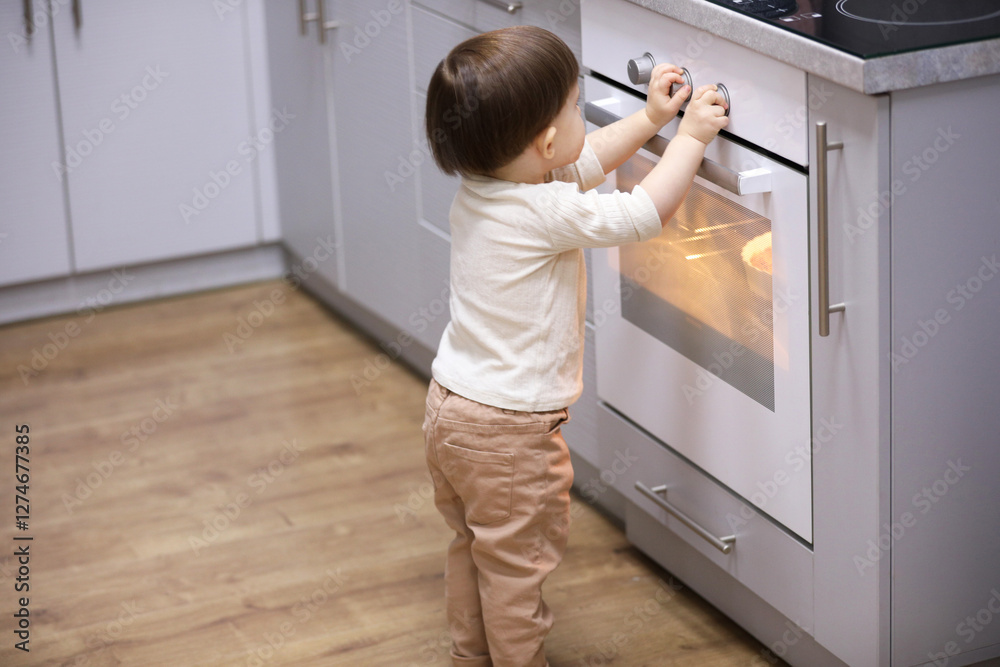 Little boy playing with oven in kitchen. Dangerous situation Little boy playing with oven in kitchen. Dangerous situation
