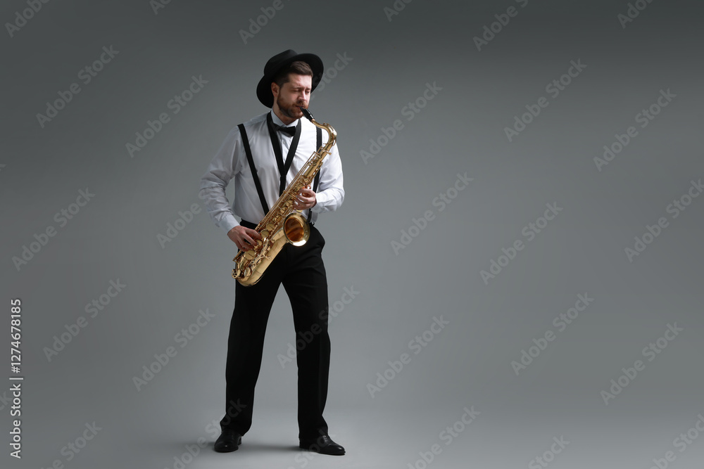 Naklejka premium Professional musician playing saxophone on grey background