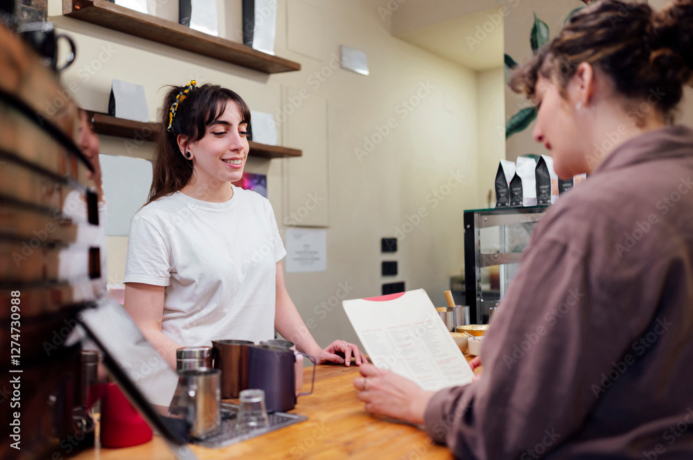 Barista smiling at customer reading menu in coffee shop Barista smiling at customer reading menu in coffee shop