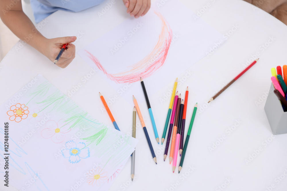Boy drawing rainbow at white table, above view Boy drawing rainbow at white table, above view