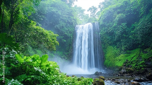 Scenic waterfall surrounded by dense jungle, mist rising from the cascading water.