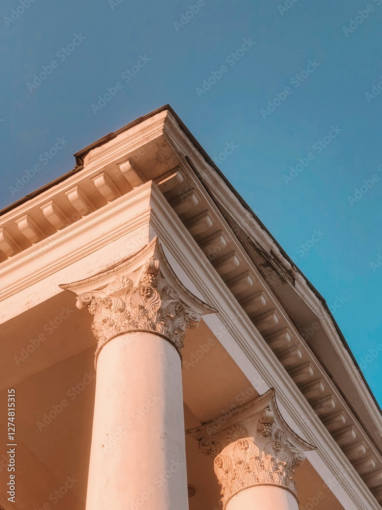 Fototapeta premium Round beige stone columns support the roof of a building on a summer day