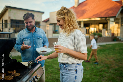 Family enjoying backyard barbecue grilling food and drinking