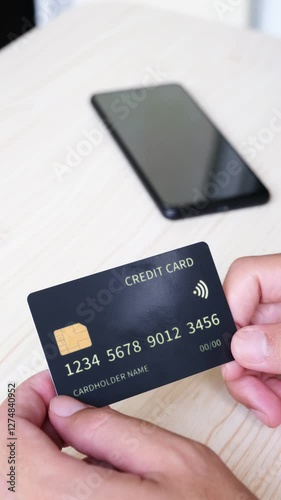 Person hands showing black credit card with phone on the table as background