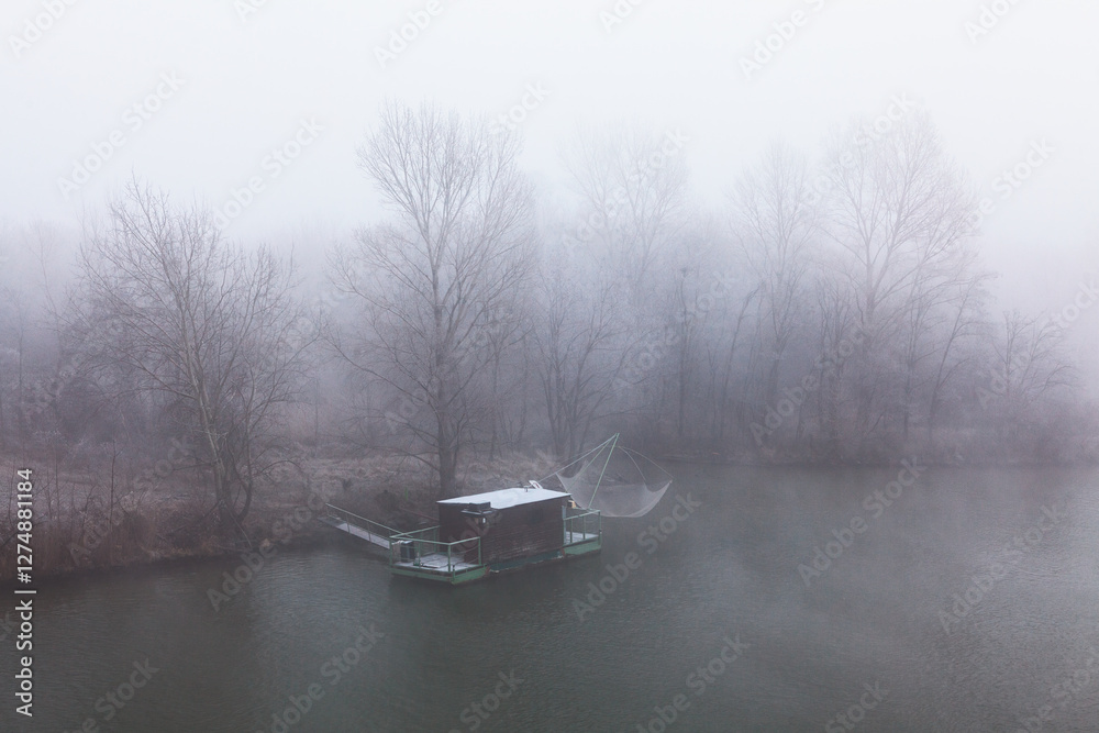 Foggy river scene with a small fishing hut on a floating platform. Bare trees fade into the mist, creating a mysterious, tranquil atmosphere. Muted tones and soft light enhance the dreamlike mood