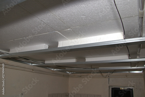 Unterkonstruktion aus Metallprofilen für Gipskartondecke. Darüber Styroporplatten und Dampfsperre.
