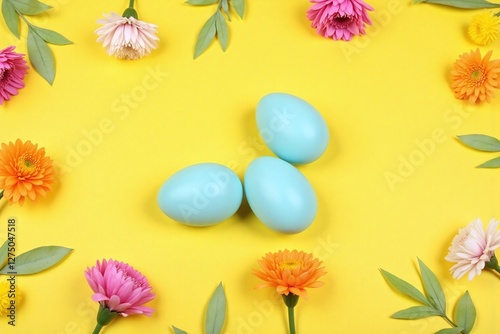 Easter themed yellow background with blue eggs flowers leaves photo