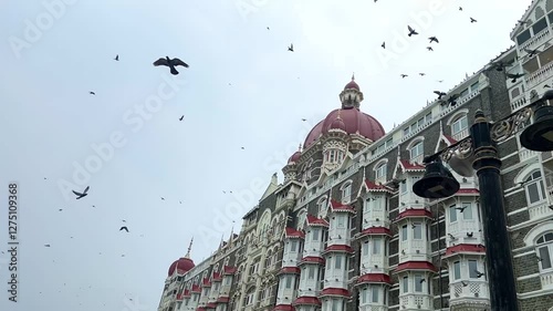 Closeup view of Taj Mahal Palace Hotel a Five-star Luxury Hotel, Situated Next To Gateway Of India. Famous Tourist Attraction In Mumbai India.Pigeons Fly In Slow Motion Above Taj Mahal Hotel.