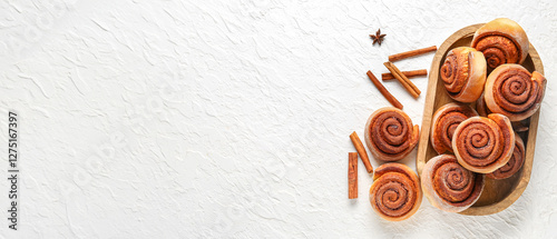 Wooden tray with tasty cinnamon rolls on white background photo