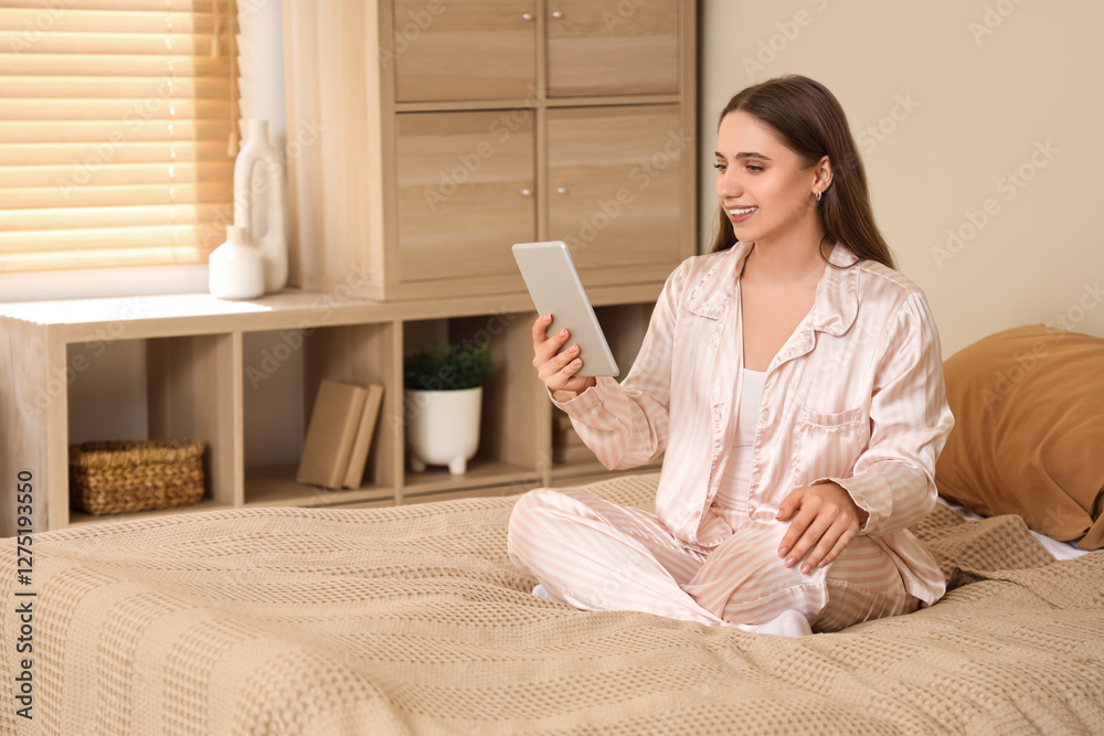 Young pretty woman in pajamas chatting with tablet on bed at home Young pretty woman in pajamas chatting with tablet on bed at home