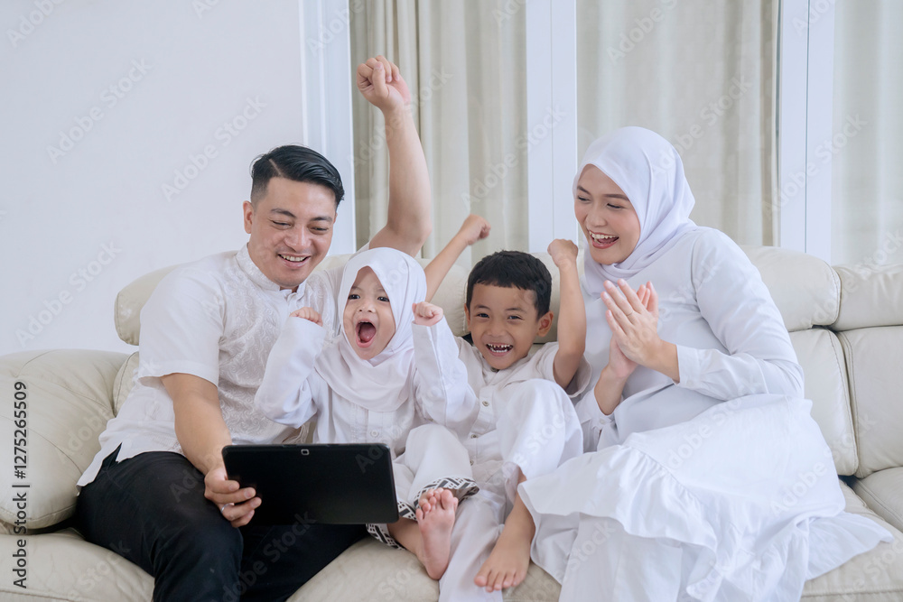 Fototapeta premium Cheerful Muslim Family Celebrating Together While Watching Tablet at Home