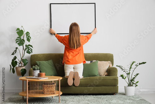 Woman hanging blank picture...